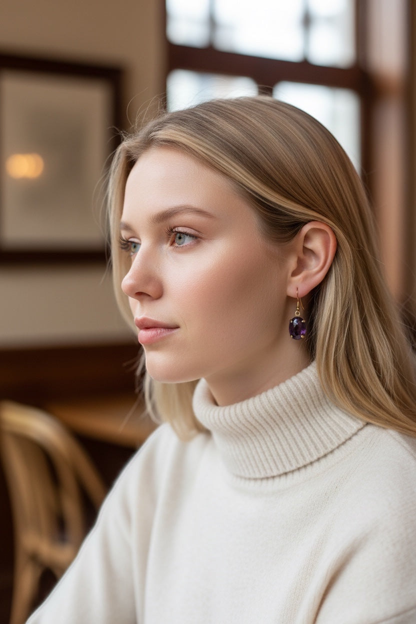 Bedrock Rose amethyst prong set oval drop earrings on a model wearing a cream turtleneck sweater.
