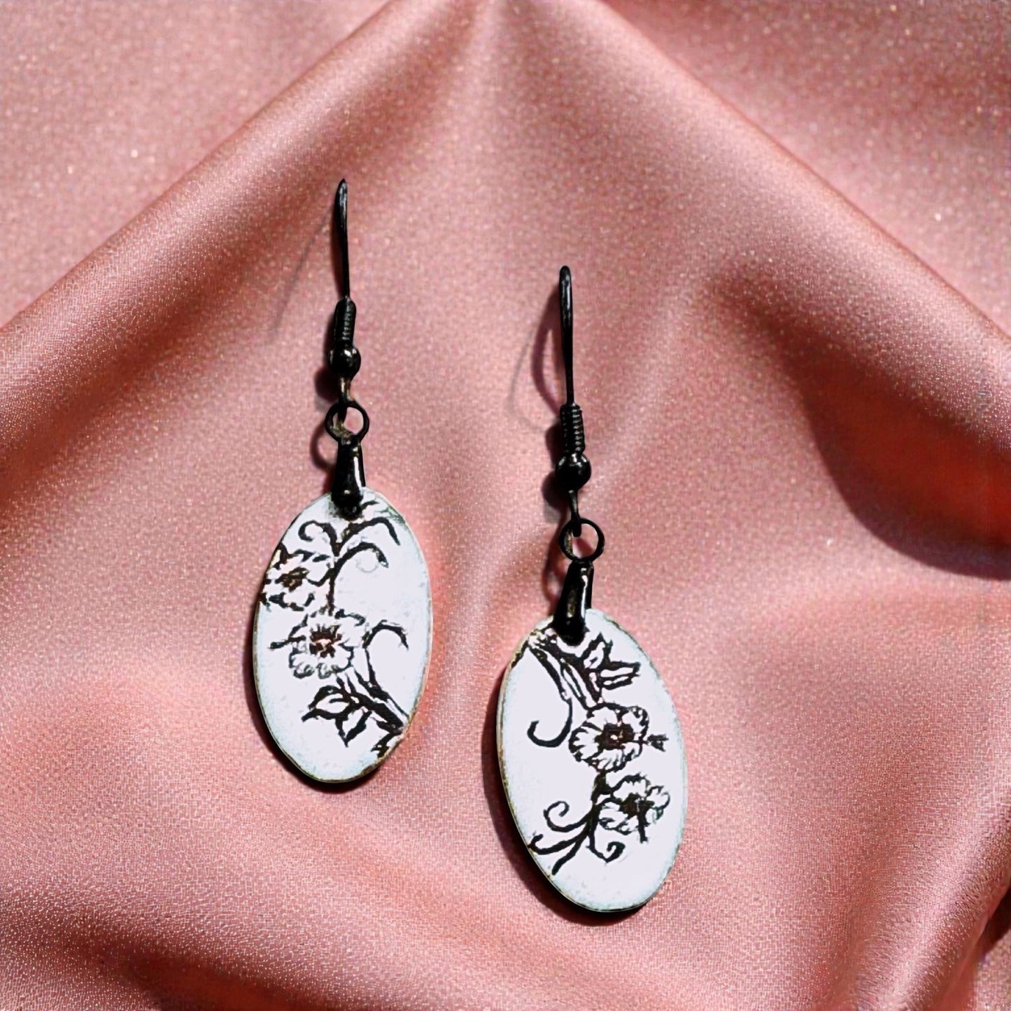 Bedrock Rose slender oval dangle earrings with black floral enamel on white, 1.5" length.