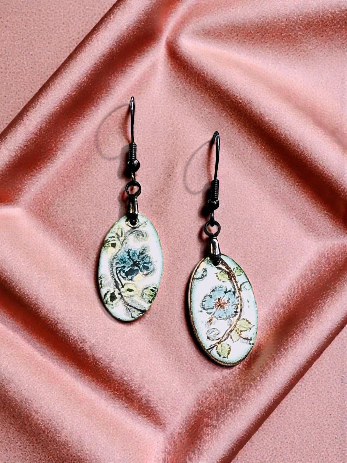 Bedrock Rose oval enameled dangle earrings with hand-painted blue flowers and green leaves on white.