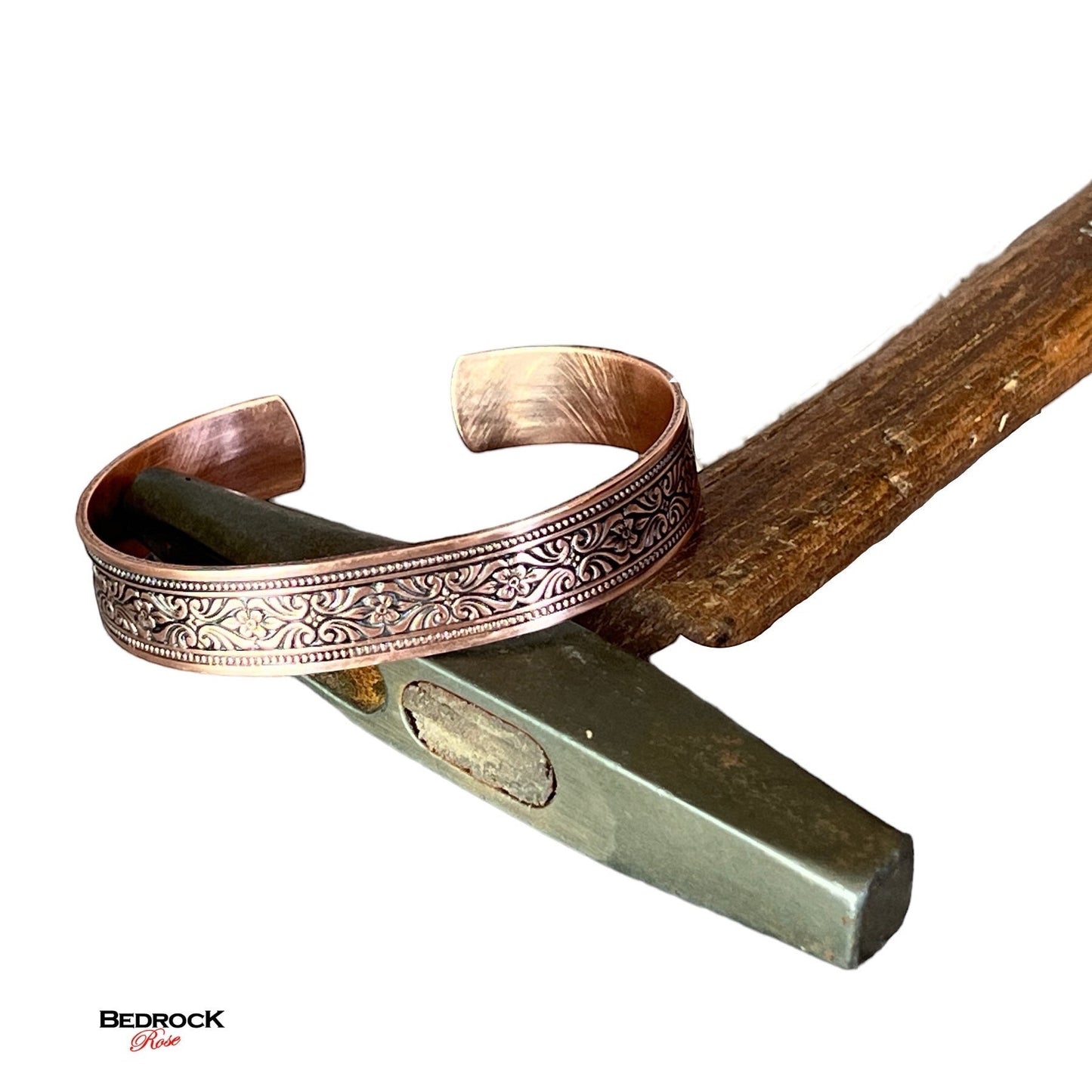 Bedrock Rose copper cuff bracelet with intricate scrollwork and floral design, polished finish.