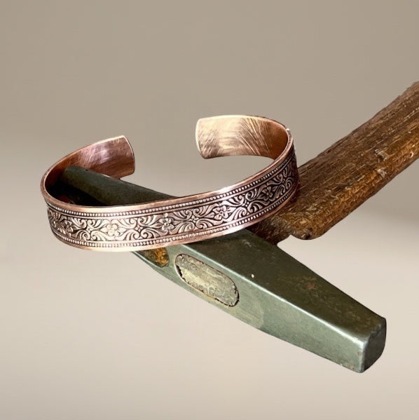 Bedrock Rose copper cuff bracelet with intricate scrollwork and floral patterns, polished finish.