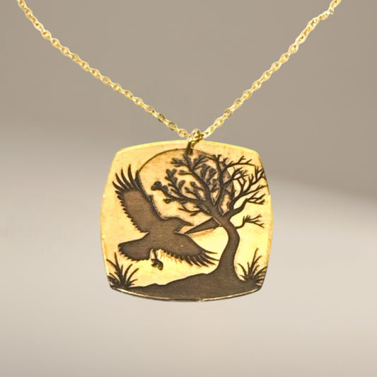 Bedrock Rose gold-plated brass necklace with laser-engraved crow, tree, and moon pendant on a gold chain.