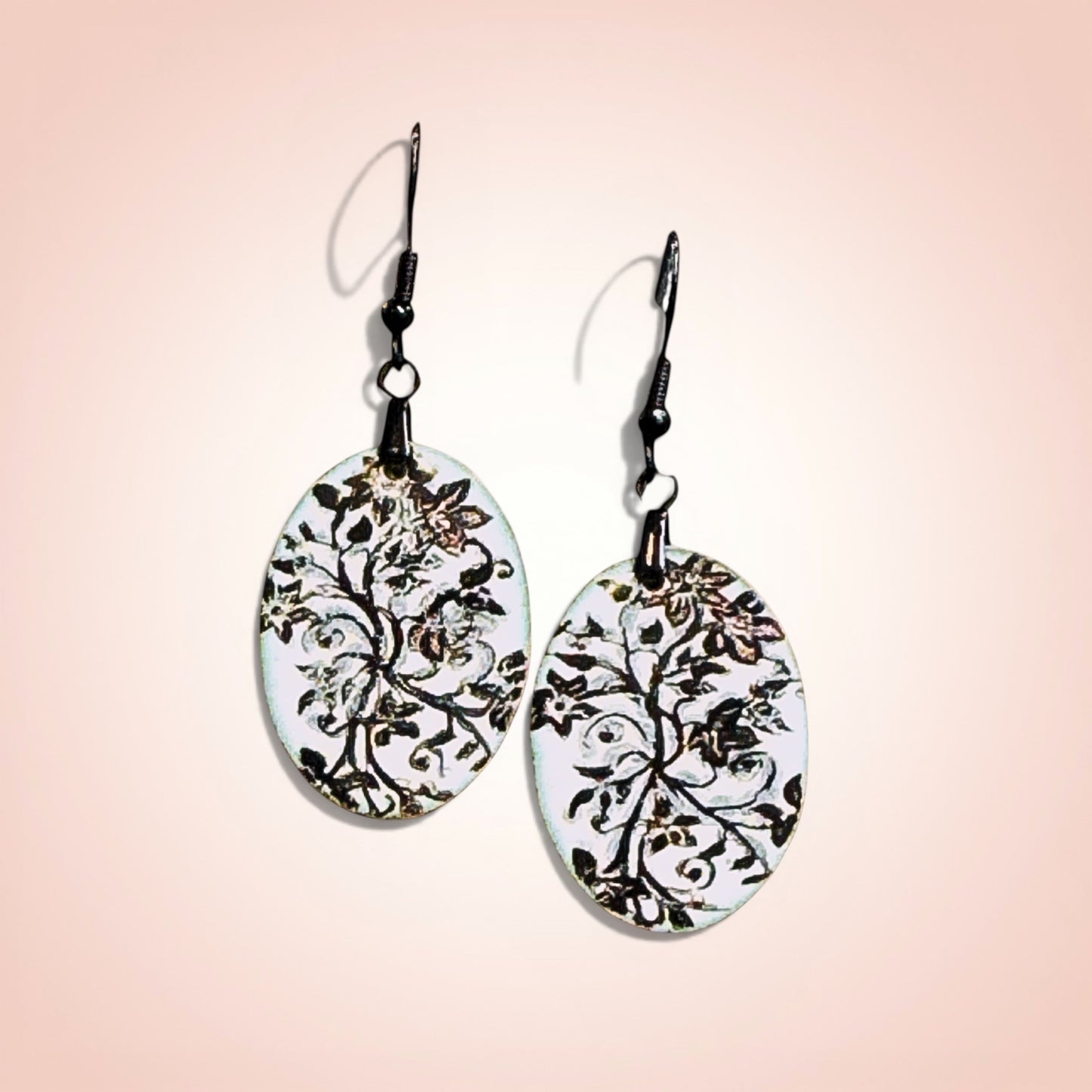 Bedrock Rose oval copper earrings with white enamel and black floral design. Artisan handcrafted statement jewelry.
