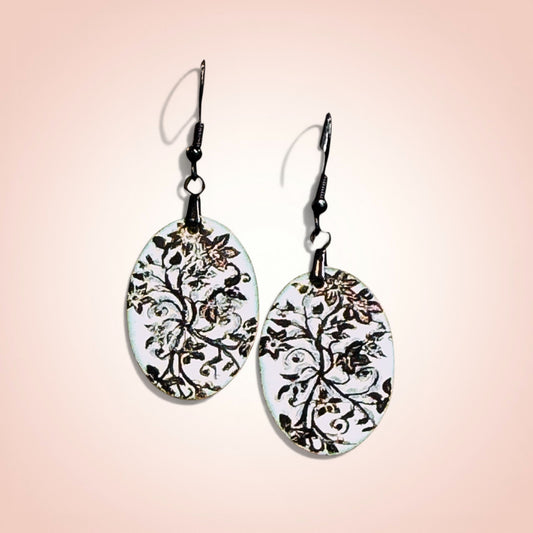 Bedrock Rose oval copper earrings with white enamel and black floral design. Artisan handcrafted statement jewelry.