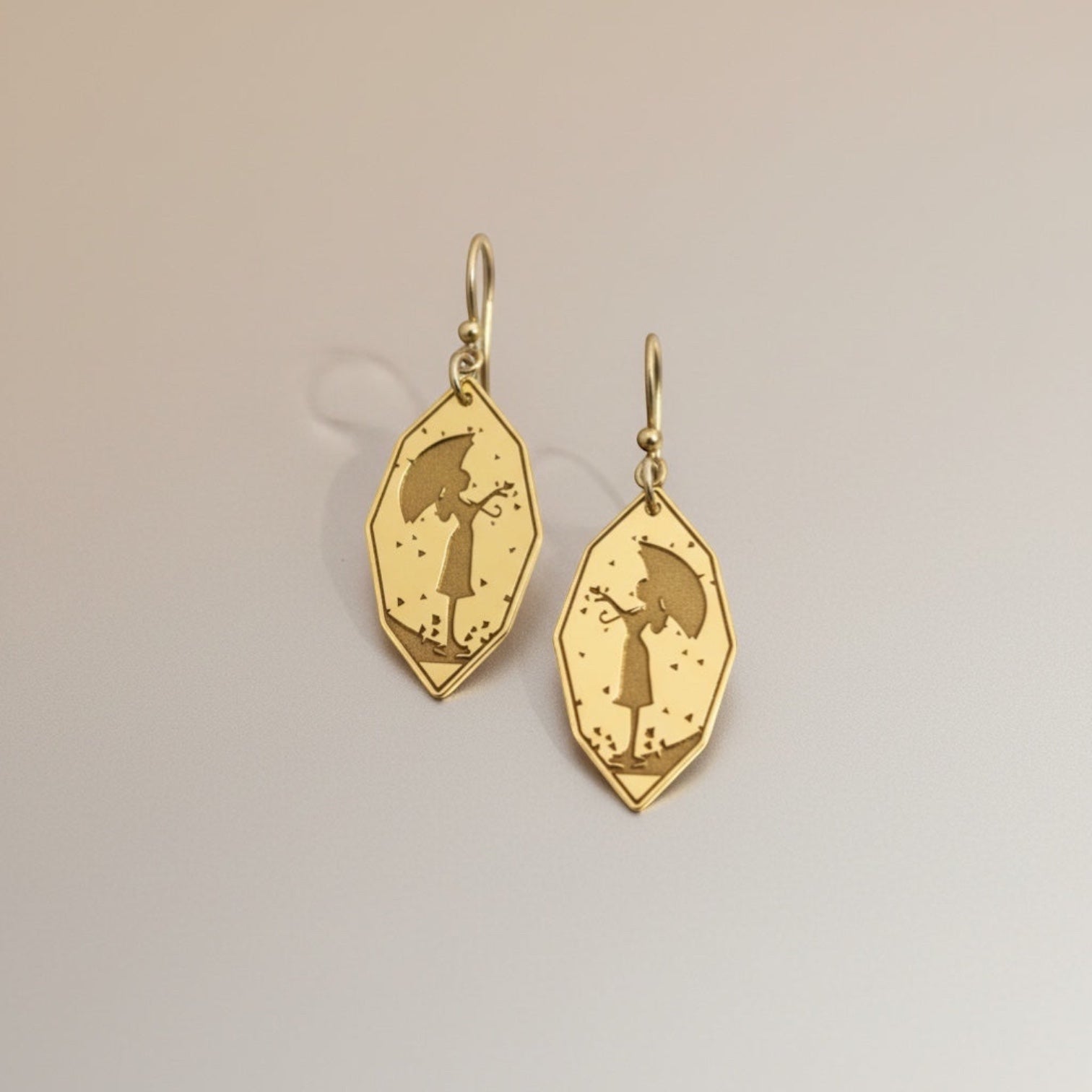 Bedrock Rose gold-plated earrings featuring a silhouette of a girl holding an umbrella, with falling leaves detail.