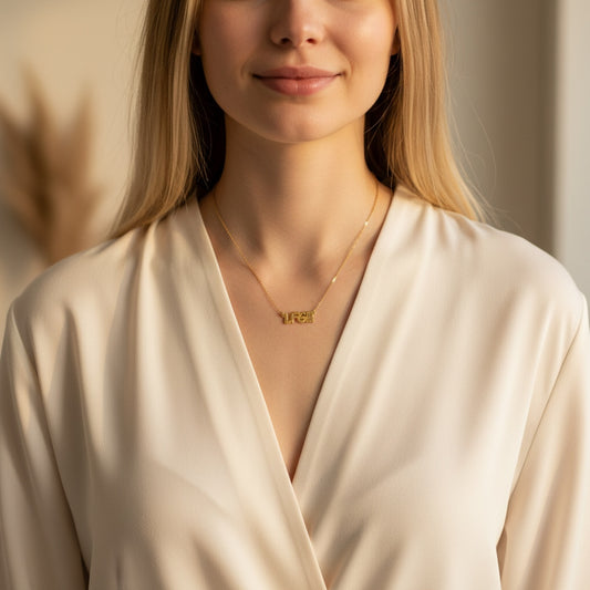 Bedrock Rose gold-plated brass LFG pendant necklace with a 16" chain and 2" extension. Features bold lettering and is surrounded by purple flowers.