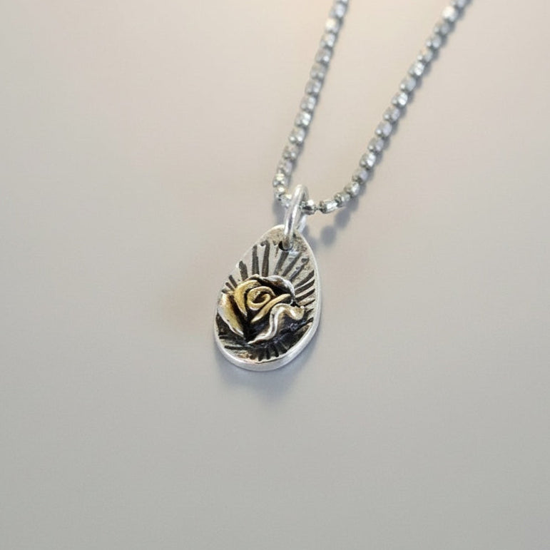 Bedrock Rose silver pendant with 24K gold-plated Floribunda rose detail and sunburst engraving.