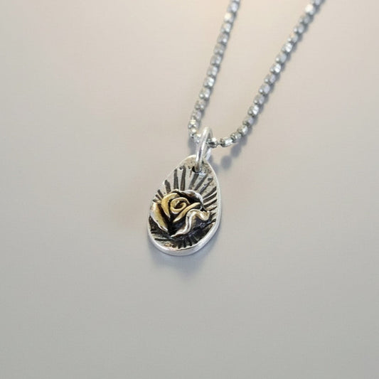 Bedrock Rose silver pendant with 24K gold-plated Floribunda rose detail and sunburst engraving.