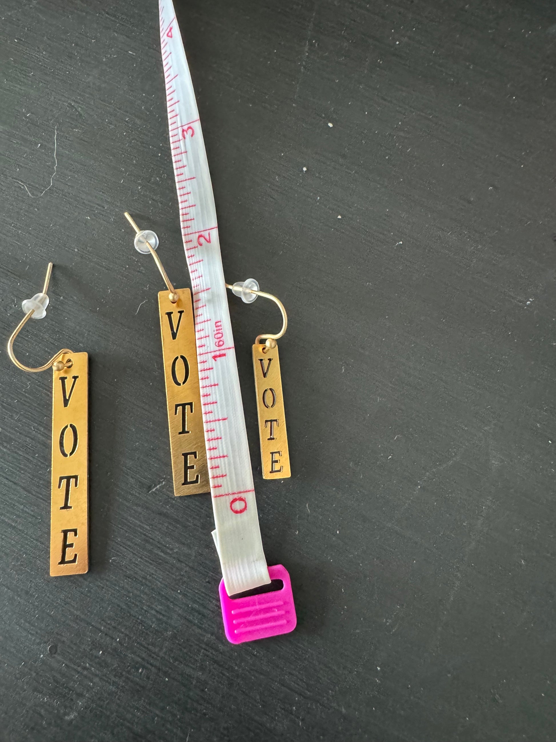 Vote earrings two sizes next to ruler