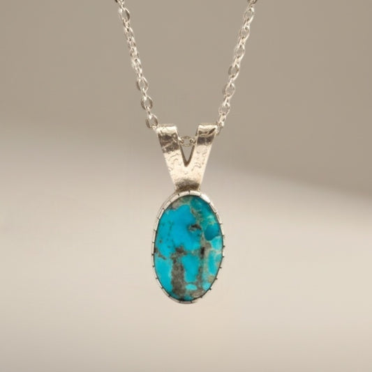Bedrock Rose dainty Kingman Turquoise pendant in sterling silver. Oval blue turquoise with matrix detail on an 18" chain.