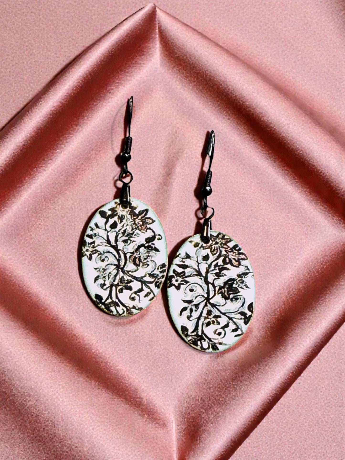 Bedrock Rose oval copper earrings with white enamel and black floral design. Artisan crafted botanical dangles.