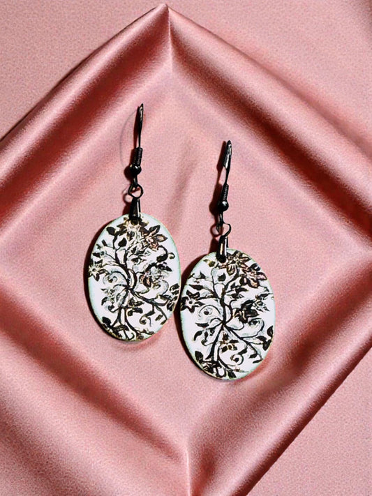 Bedrock Rose oval copper earrings with white enamel and black floral design. Artisan crafted botanical dangles.