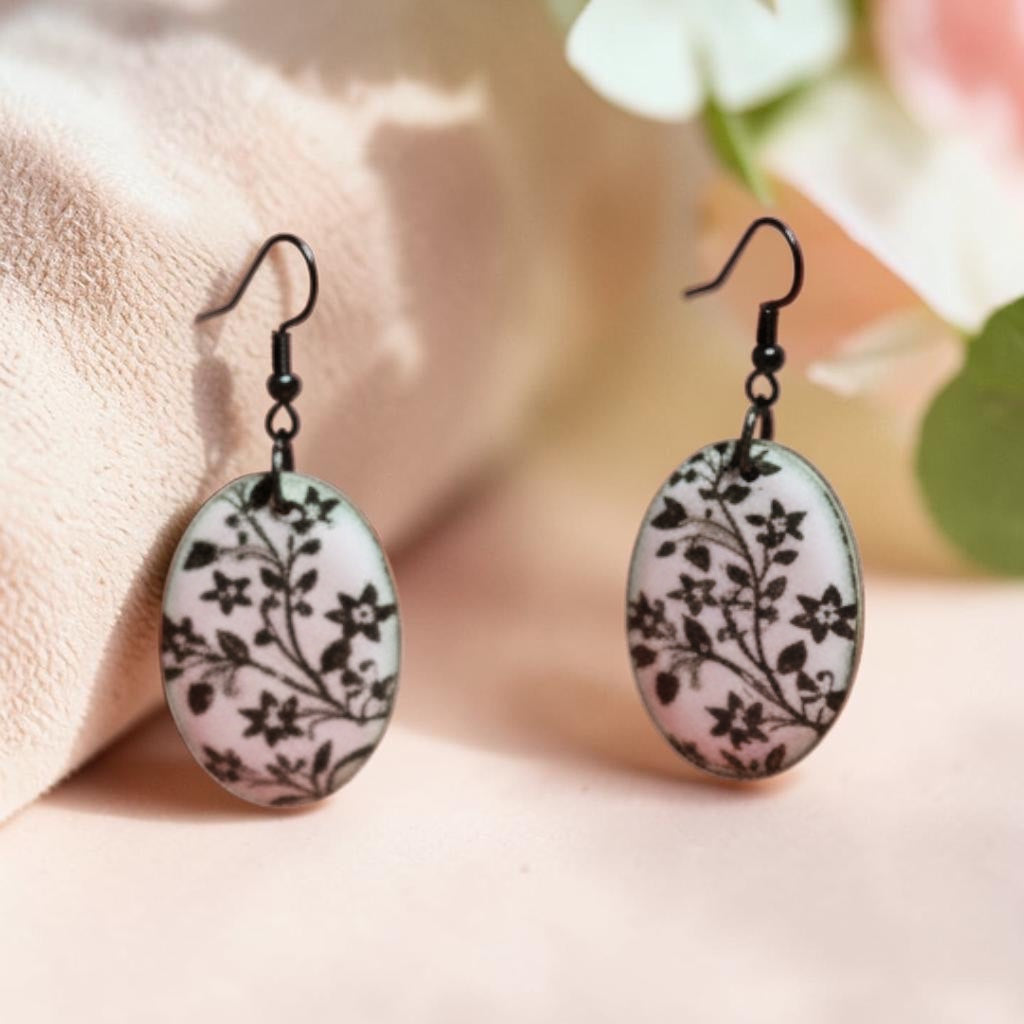 Bedrock Rose oval dangle earrings with black monochromatic floral design on a white enamel base, copper core.