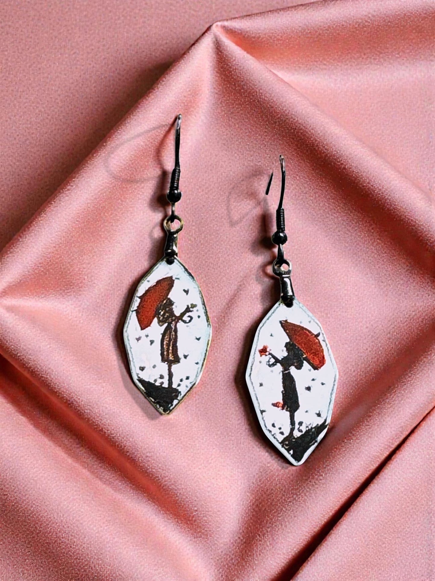 Bedrock Rose artisan shield earrings featuring hand-painted red umbrellas and silhouettes on white enamel.
