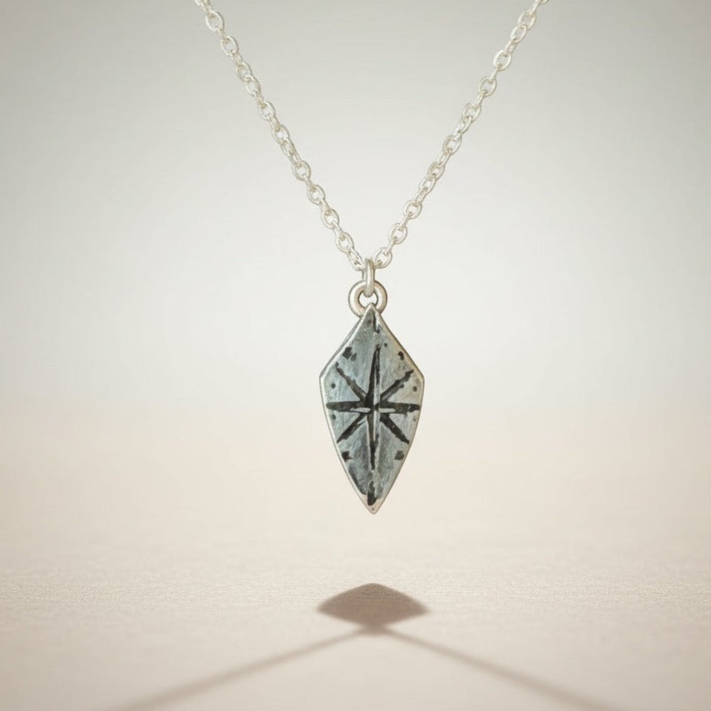 Bedrock Rose silver compass rose shield pendant necklace with a sterling silver cable chain. Adventure-inspired jewelry.