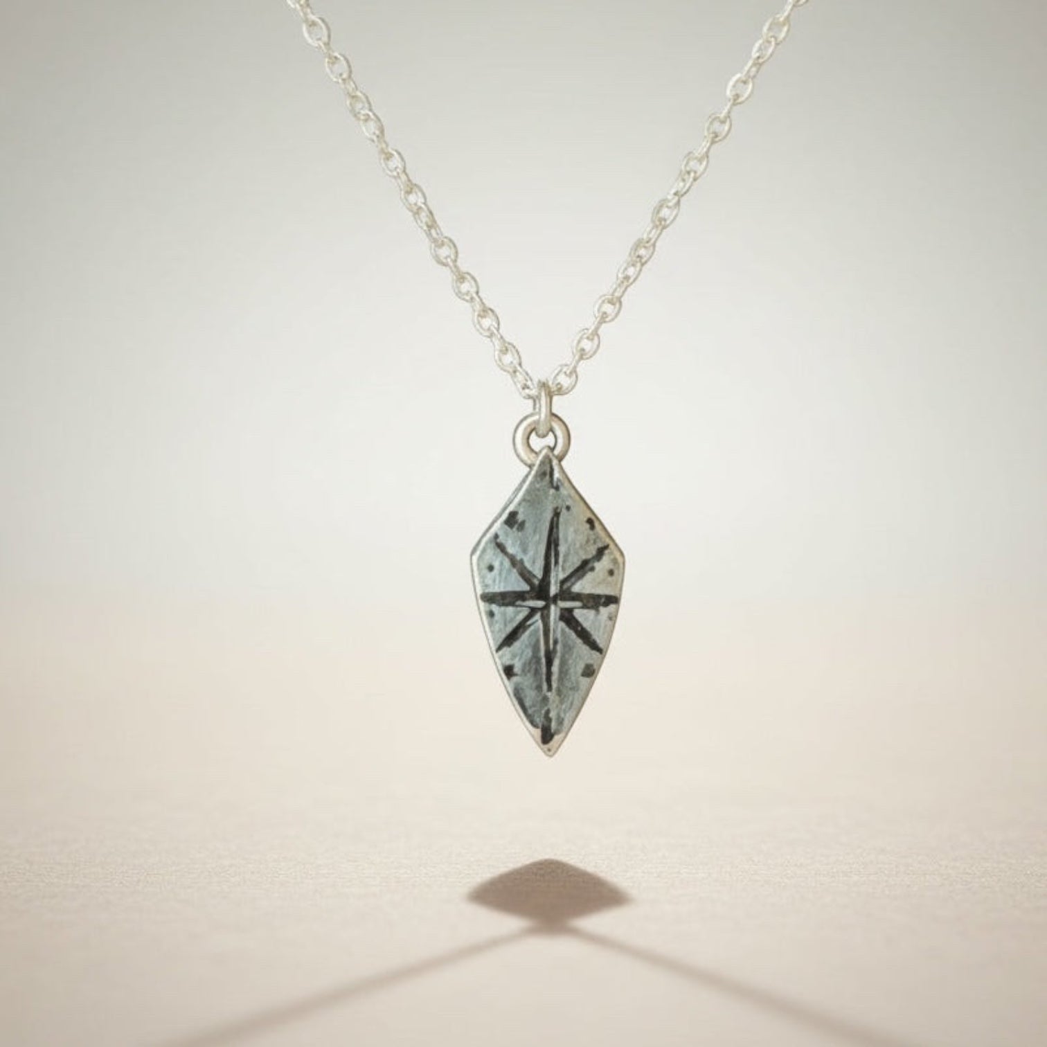 Bedrock Rose silver compass rose shield pendant necklace with a sterling silver cable chain. Adventure-inspired jewelry.
