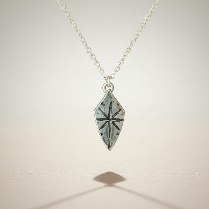 Bedrock Rose silver compass rose shield pendant necklace with a sterling silver cable chain. Adventure-inspired jewelry.