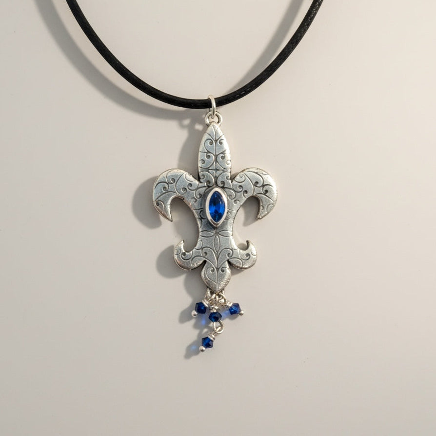 Bedrock Rose sterling silver fleur-de-lis pendant with blue marquis gemstone and dangling blue crystals.