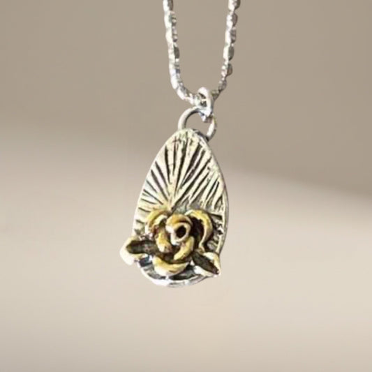 Bedrock Rose silver and gold rose pendant on a faceted ball chain necklace. Rose detail with sunburst background.