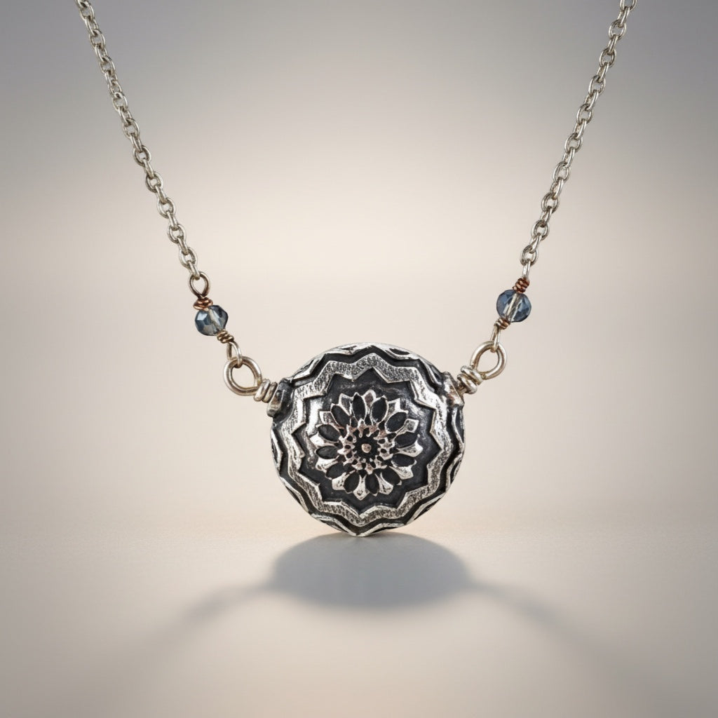 Bedrock Rose double-sided silver mandala pendant necklace with blue crystal accents. Intricate floral design.