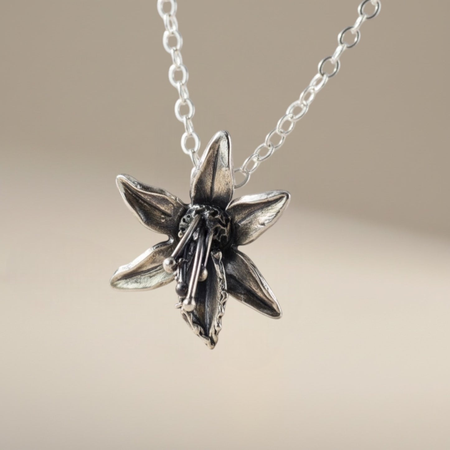 Bedrock Rose sterling silver orchid pendant necklace with delicate petals and intricate stamen detail.