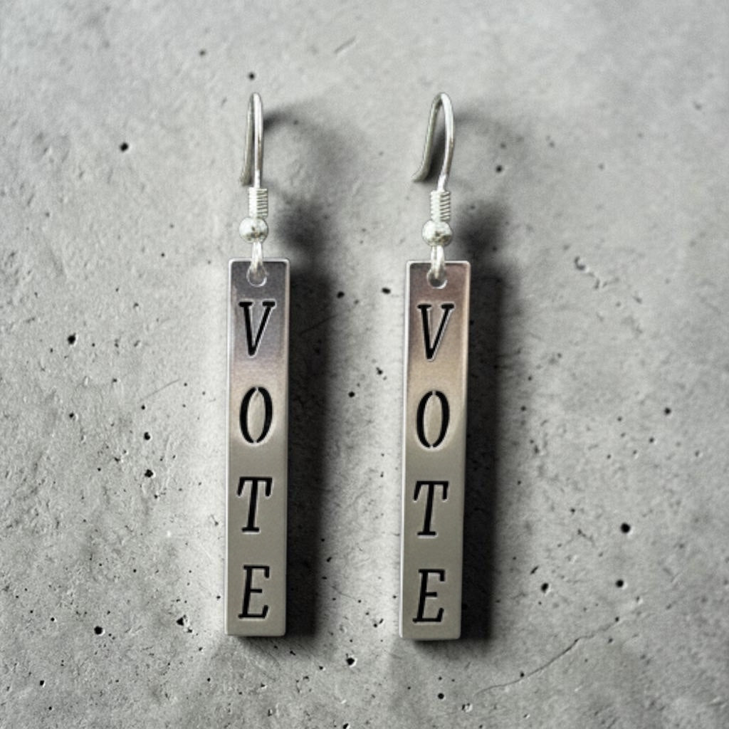 Bedrock Rose silver dangling earrings with the word "Vote" in block letters. Laser-cut metal, ideal for political statements.