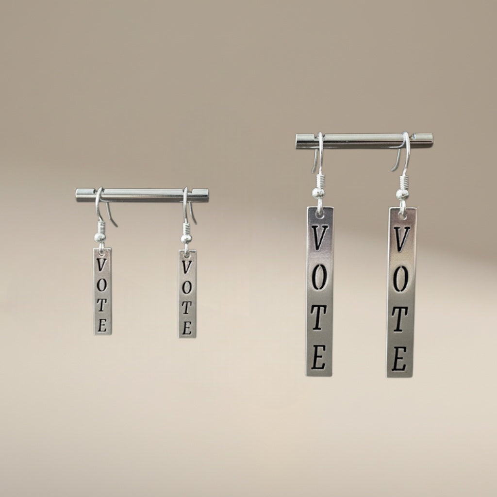 Bedrock Rose silver dangling earrings with the word "Vote" laser-cut in block letters. Democracy jewelry.
