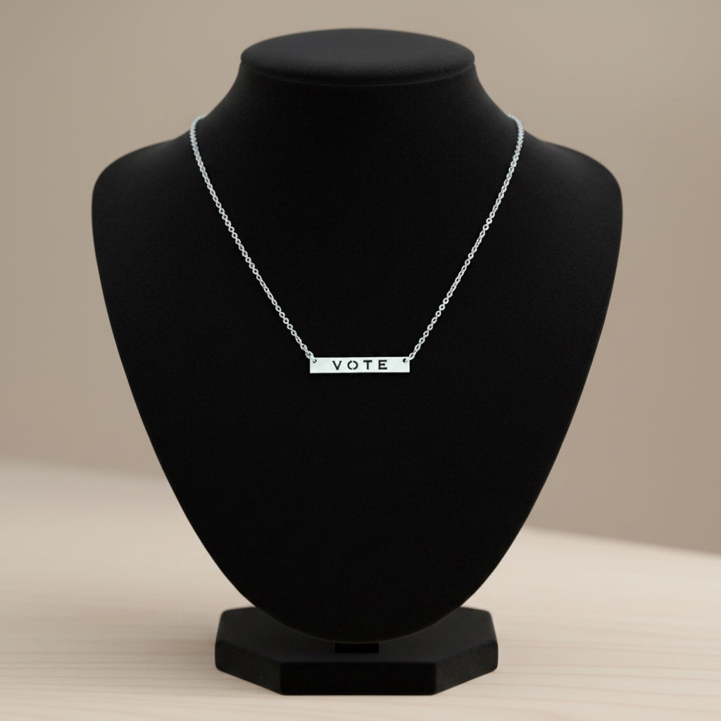 Bedrock Rose silver vote necklace. Sterling silver bar pendant with laser-cut "VOTE" text and a faceted hypoallergenic stainless steel chain.