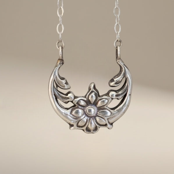 Bedrock Rose Sterling Silver floral crescent pendant necklace with a flower motif. Feminine solar eclipse jewelry.