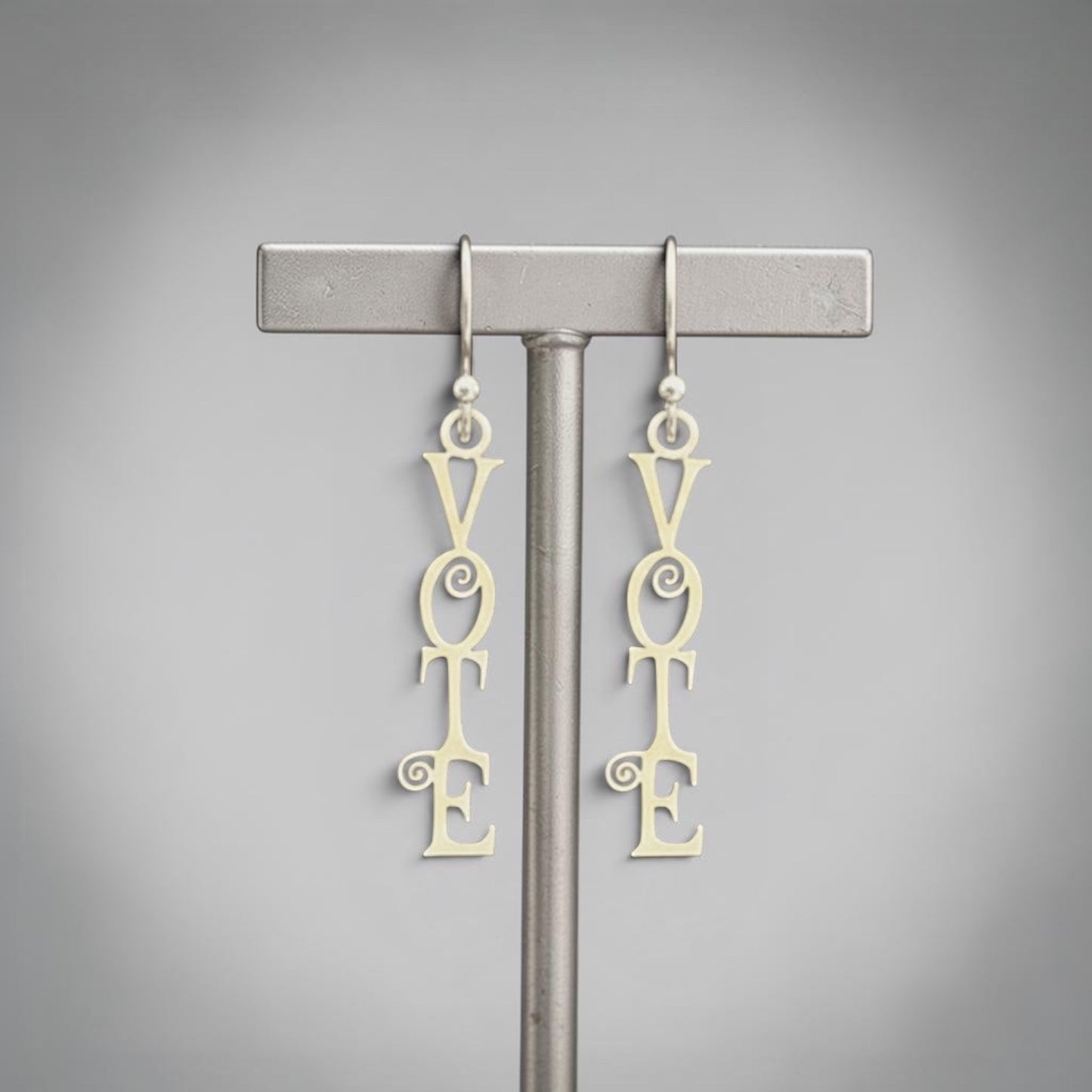Bedrock Rose sterling silver dangling earrings with the word "Vote" in a fancy scroll design. Laser-cut, elegant, and perfect for showing support for democracy.