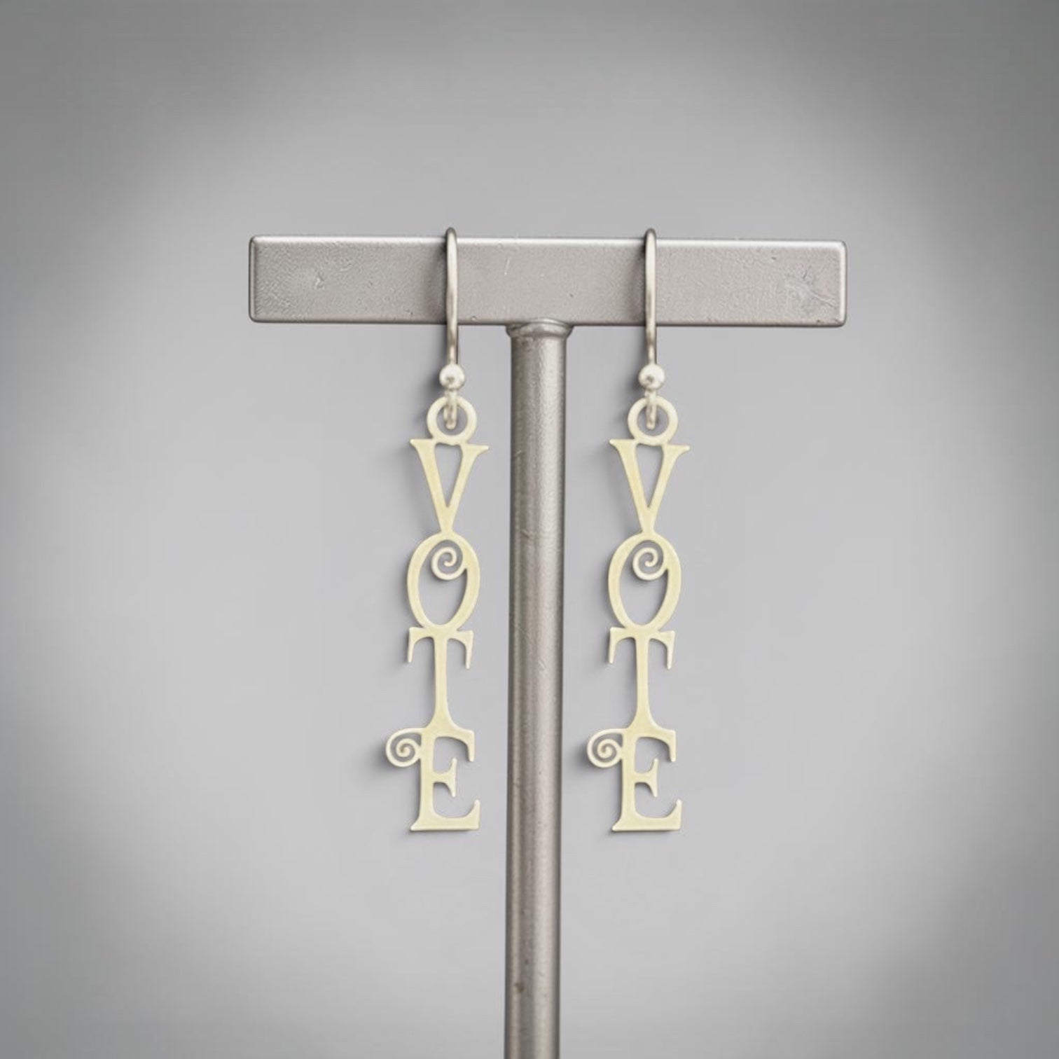 Bedrock Rose sterling silver dangling earrings with the word "Vote" in a fancy scroll design. Laser-cut, elegant, and perfect for showing support for democracy.
