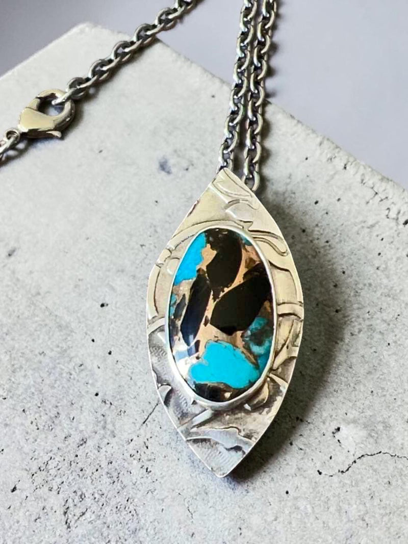Bedrock Rose sterling silver pendant with Kingman turquoise, onyx, and bronze inlay. Features a leaf-shaped frame and a 19" chain.