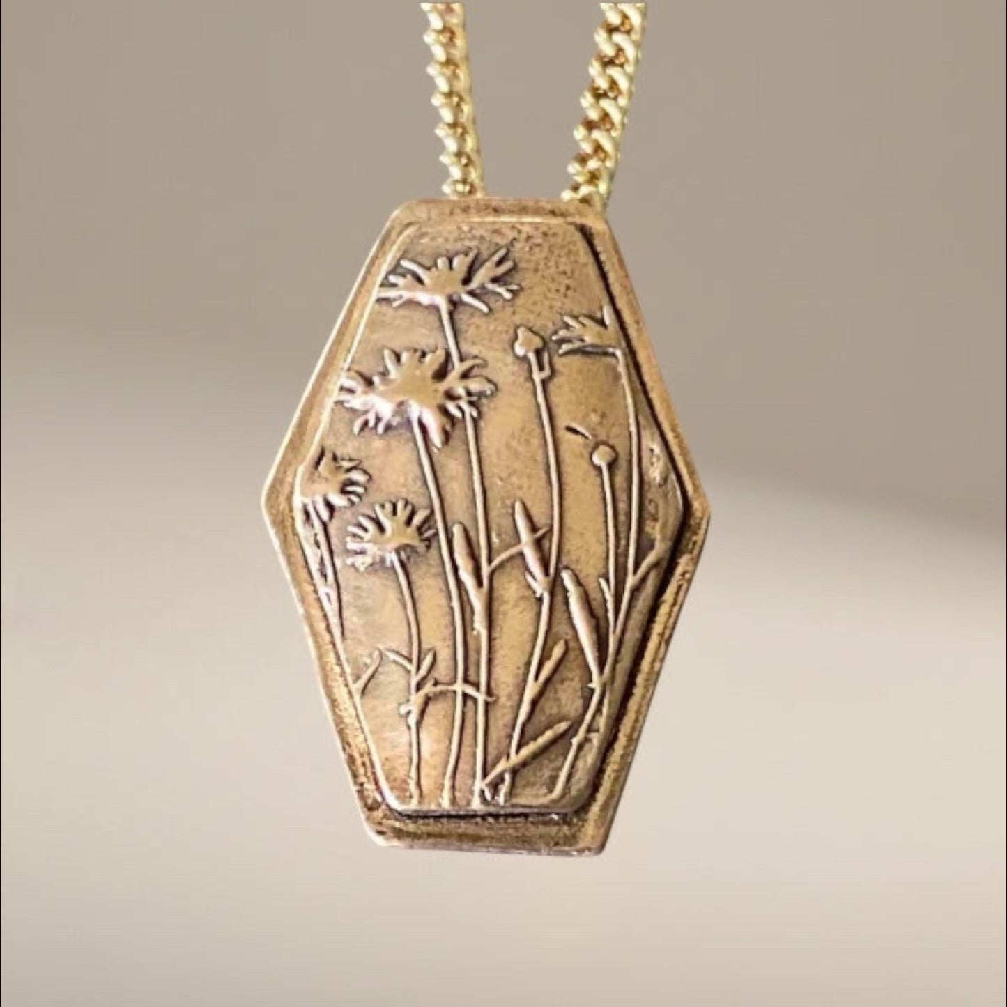 Bedrock Rose wildflower pendant in rose bronze with a detailed floral engraving and a gold-tone chain.