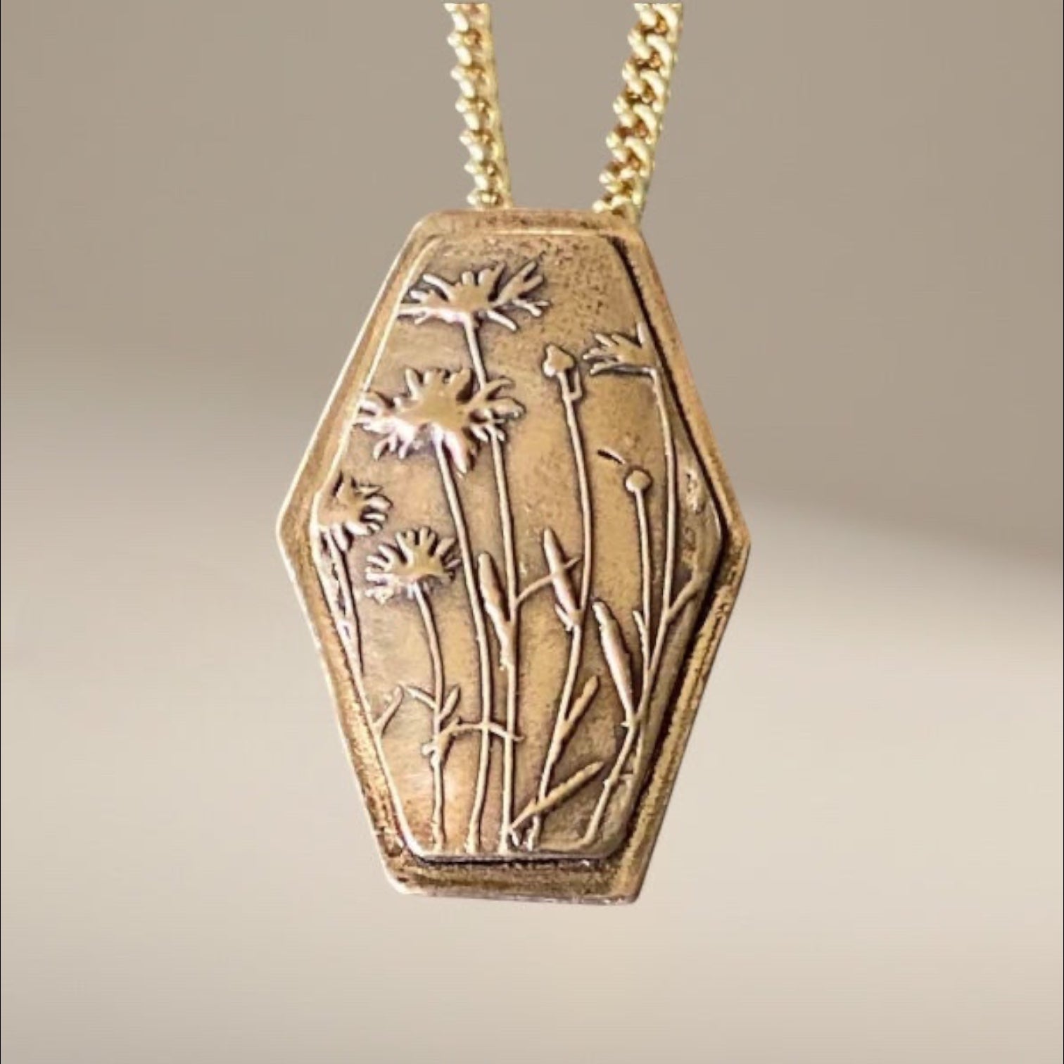 Bedrock Rose wildflower pendant in rose bronze with a detailed floral engraving and a gold-tone chain.