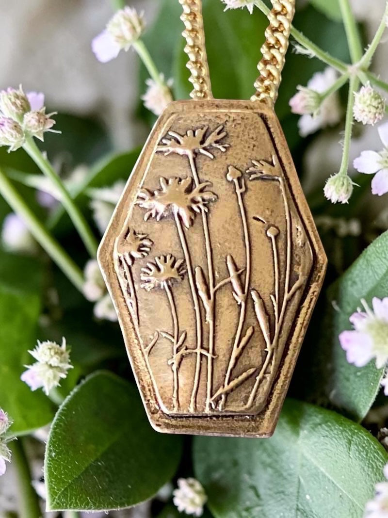 Bedrock Rose wildflower pendant in rose bronze with embossed floral design and gold chain.